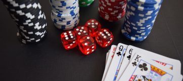 gambling chips, dice, and cards atop a black backdrop
