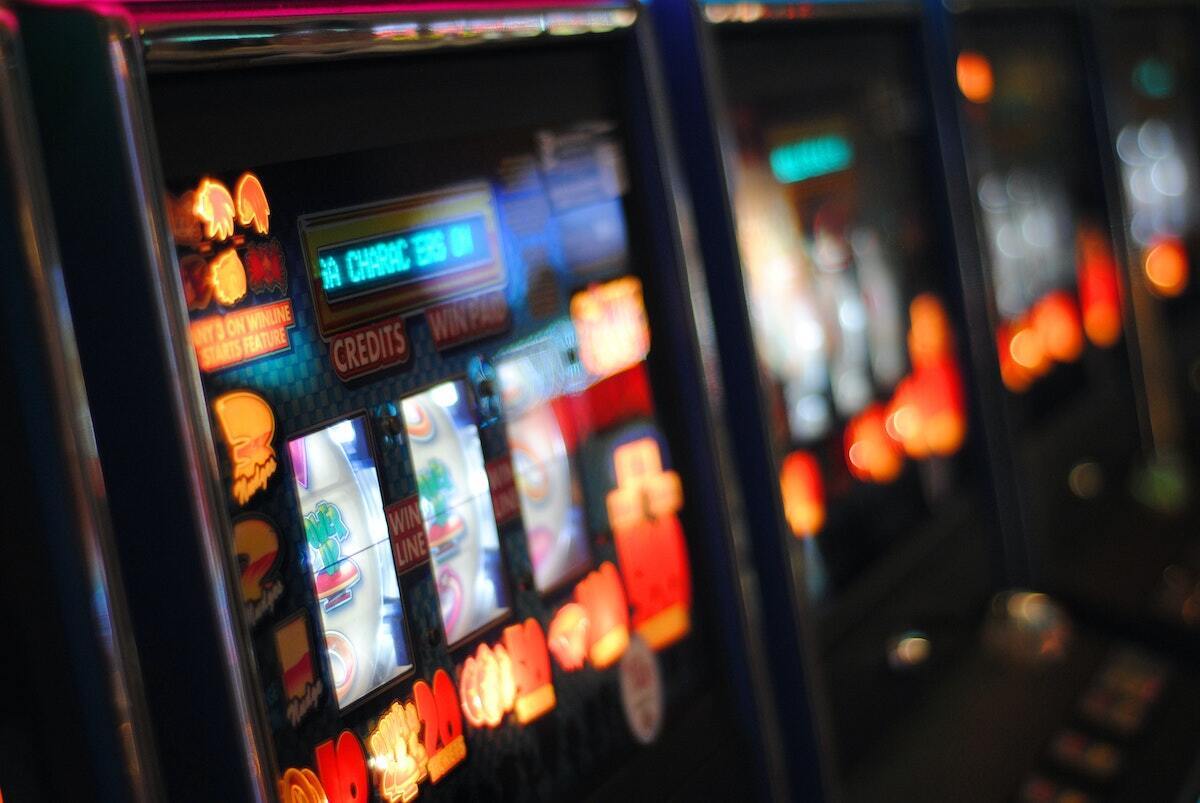 a line-up of shimmering pokie machines, slightly out of focus